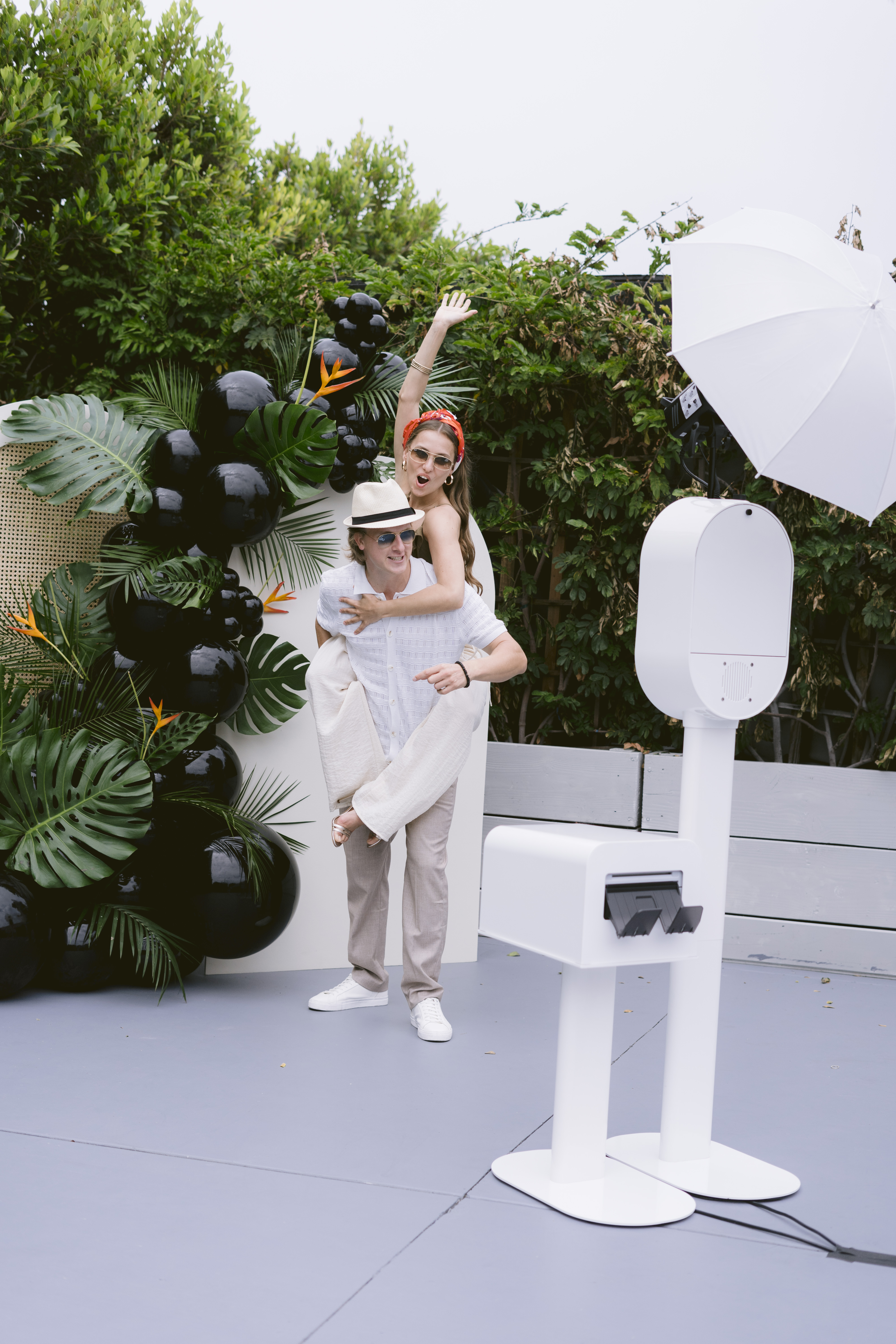 Couple laughing mid-jump for a piggyback photo at a garden party